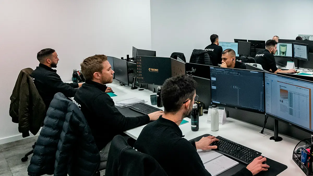 Equipe trabalhando em estação de computadores e monitores em ambiente corporativo, com profissionais analisando sistemas e documentos, em cenário relacionado a automação de processos em seguradoras.