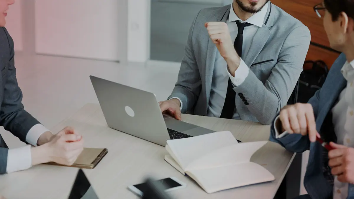 Equipe reunida em sala de reunião, com profissionais usando notebooks e discutindo estratégias no escritório. Contexto corporativo para temas como governança de IA em seguradoras.